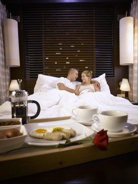 在舒适的床上懒洋洋地吃早餐的情侣