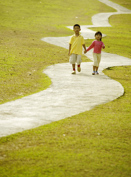 男孩和女孩手拉手在公园散步