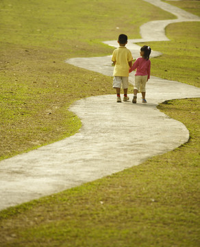 男孩和女孩手拉手在公园散步