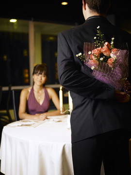 男人把花束放在背后，女人看着他