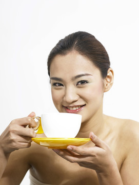 亚洲女士拿着茶碟和杯子摆姿势