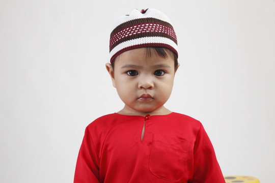 马来男孩穿着红色传统布料看着相机