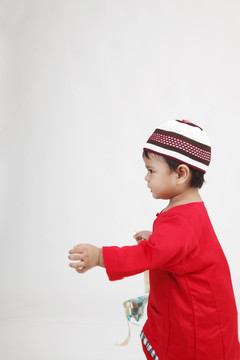马来男孩穿着红色的传统布拿着装饰性的斗篷