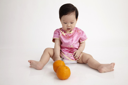 中国宝宝穿着秋千玩橘子