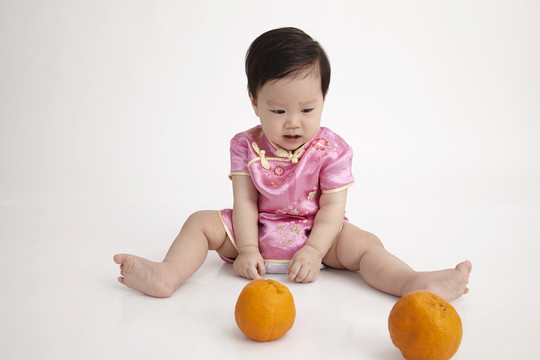 中国宝宝穿着秋千玩橘子