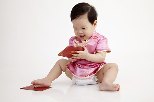 中国宝宝穿着雪松坐在工作室里玩红包