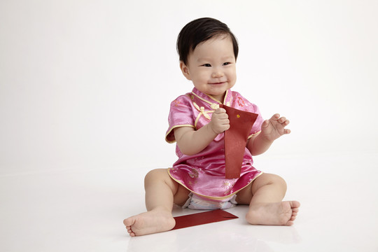 中国宝宝穿着雪松坐在工作室里玩红包