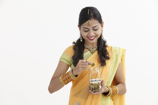 穿着迷人传统服装的印度女人手里拿着一个储蓄罐