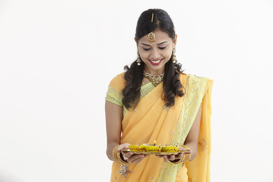 穿着迷人传统服装的印度女人，手里拿着一盘迪亚斯