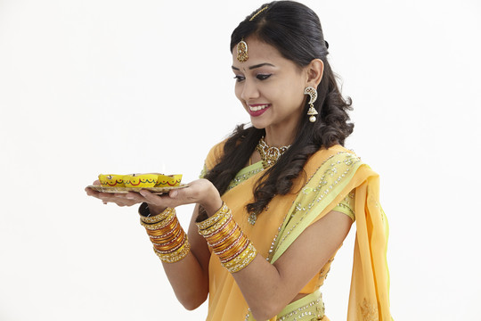 穿着迷人传统服装的印度女人，手里拿着一盘迪亚斯
