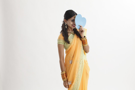一名印度妇女拿着一张心形纸遮住自己