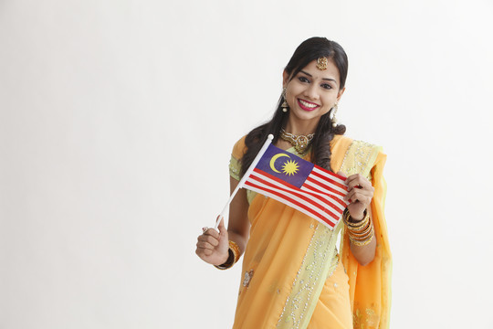 身着迷人传统服装的印度妇女手持马来西亚国旗庆祝活动