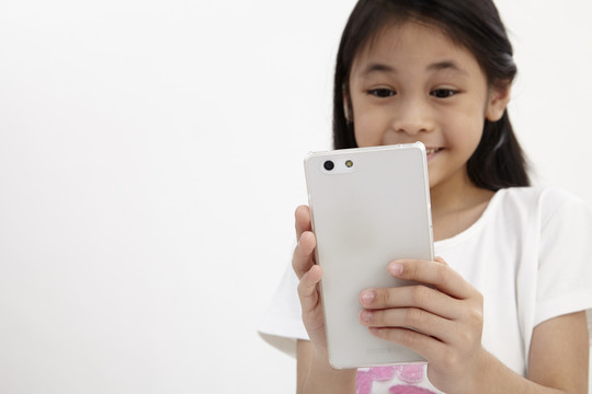 童年与科技。使用智能手机的可爱小女孩。隔离在白色上。
