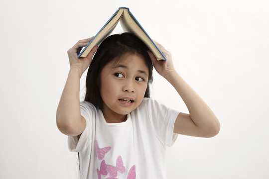 可爱的小女孩头上抱着书