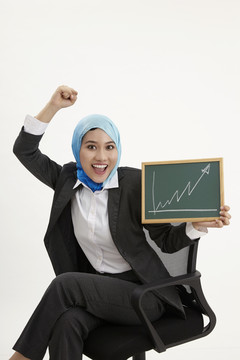 马来女商人坐在办公椅上举着黑板举着图表