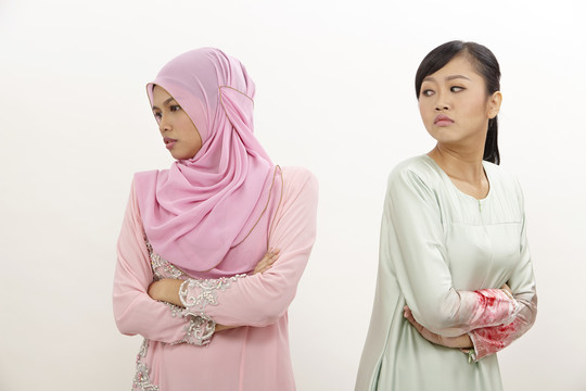 两个女朋友站在白色背景下不满并发生争吵