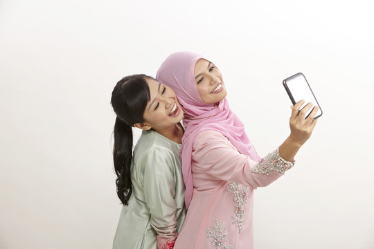 两位快乐的穆斯林年轻女子用手机自拍