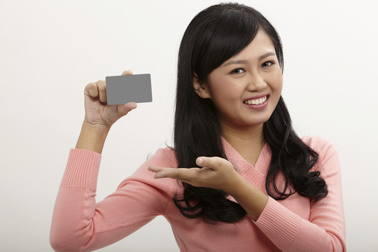 拿着白色背景的信用卡的亚洲女人