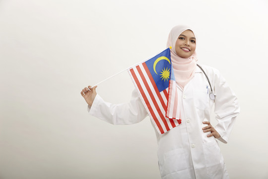 马来女医生手持白色背景的马来西亚国旗