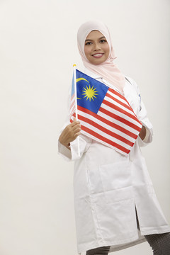 马来女医生手持白色背景的马来西亚国旗