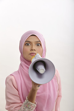 一名马来妇女对着扩音器讲话，在白色电视上发表公告