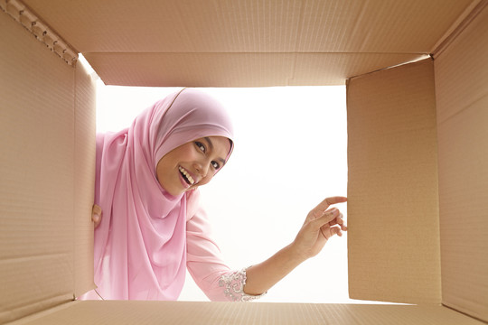 女人打开一个纸箱，看看里面，搬迁和开箱的概念