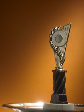 金色奖杯和奖牌放在橙色背景的桌子上。