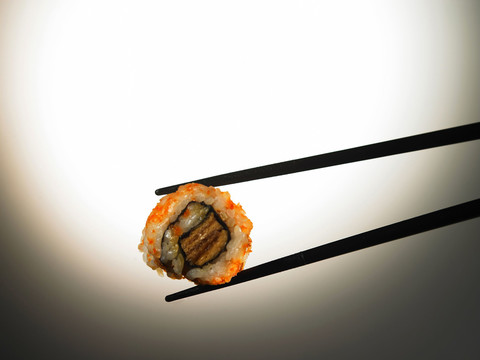 一双筷子夹起一块寿司