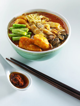 马来西亚菜一碗咖喱面配一双黑筷子和一勺酱油桑巴