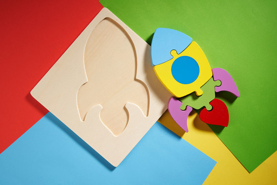 彩色木制拼图，儿童玩具的形式，火箭，在一个彩色的背景