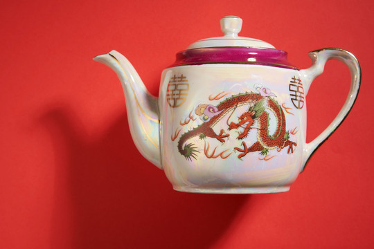 中国传统婚礼上使用的龙凤茶壶和茶杯，带有中国标志，寓意幸福。翻译：双喜临门