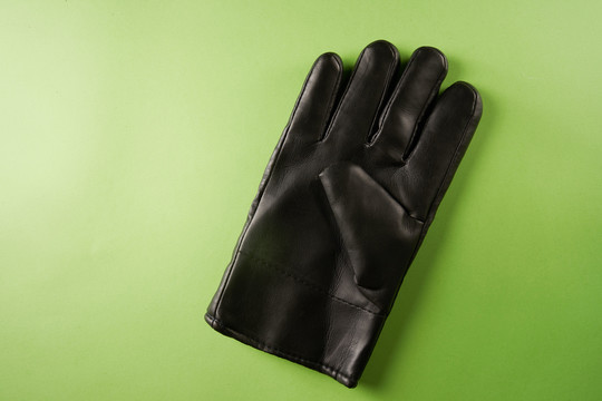 一块黑色皮革工作手套隔离在绿色背景上。