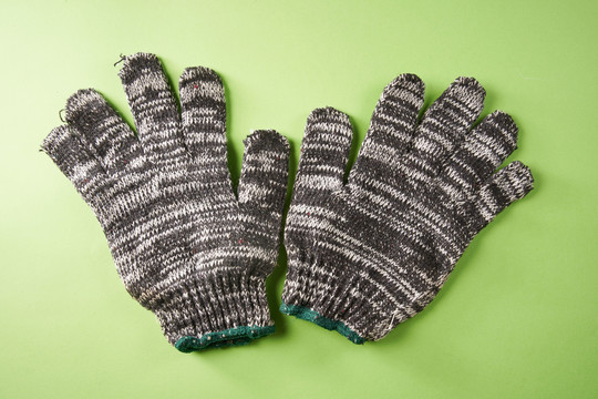 一双隔离在绿色背景上的织物工作手套。