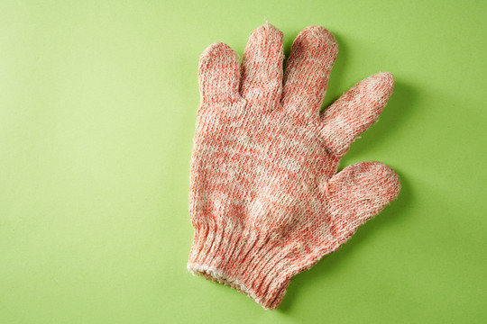 一块隔离在绿色背景上的织物工作手套。