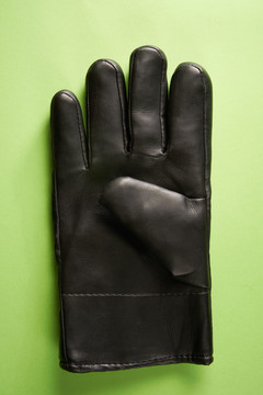 一块黑色皮革工作手套隔离在绿色背景上。