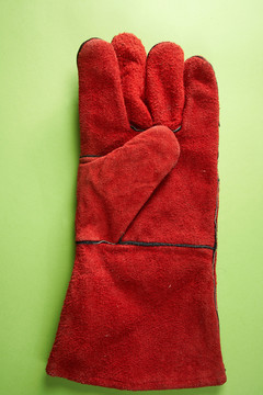 隔离在绿色背景上的红色工作手套。