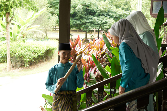 哈里拉亚（Hari Raya）期间身着传统服装的年轻人与妻子握手的画像