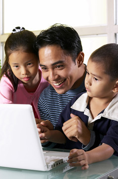 一个男人和他的孩子在笔记本电脑旁