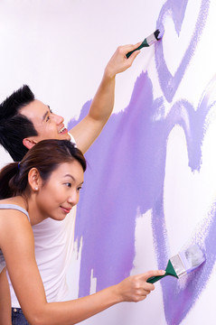 一对夫妇正在享受粉刷房子的乐趣