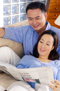一对夫妇在沙发上一起看报纸
