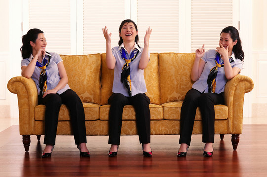 三个一模一样的女人快乐地坐在黄色的沙发上