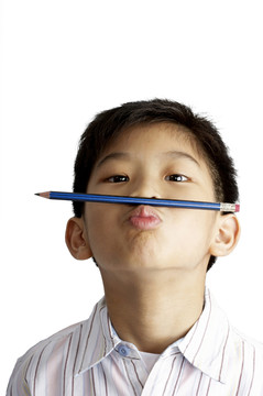 把铅笔夹在鼻子和嘴唇之间的男孩特写