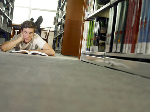 一个男人正躺在图书馆的地板上看书