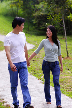 一对相爱的情侣手牵着手走在公园陡峭的路上