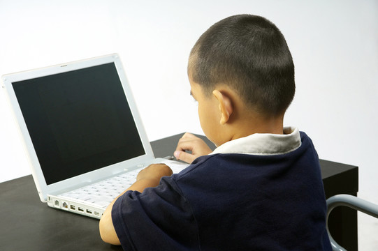 一个男孩用笔记本电脑的背照