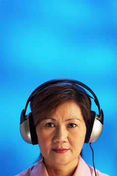 摄影棚拍摄的中年妇女用耳机听音乐