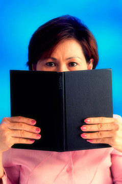摄影棚拍摄的一个女人用一本书遮住半张脸