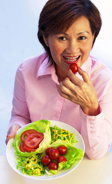 中年妇女吃西红柿的俯视图