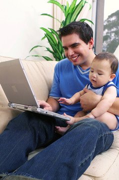 一名男子一边照看儿子一边用笔记本电脑