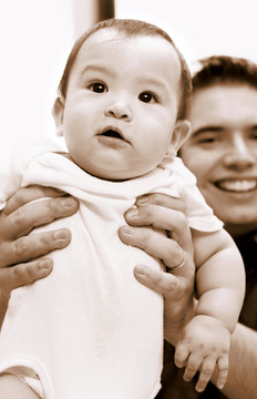 一张浅褐色的男子抱起儿子的照片